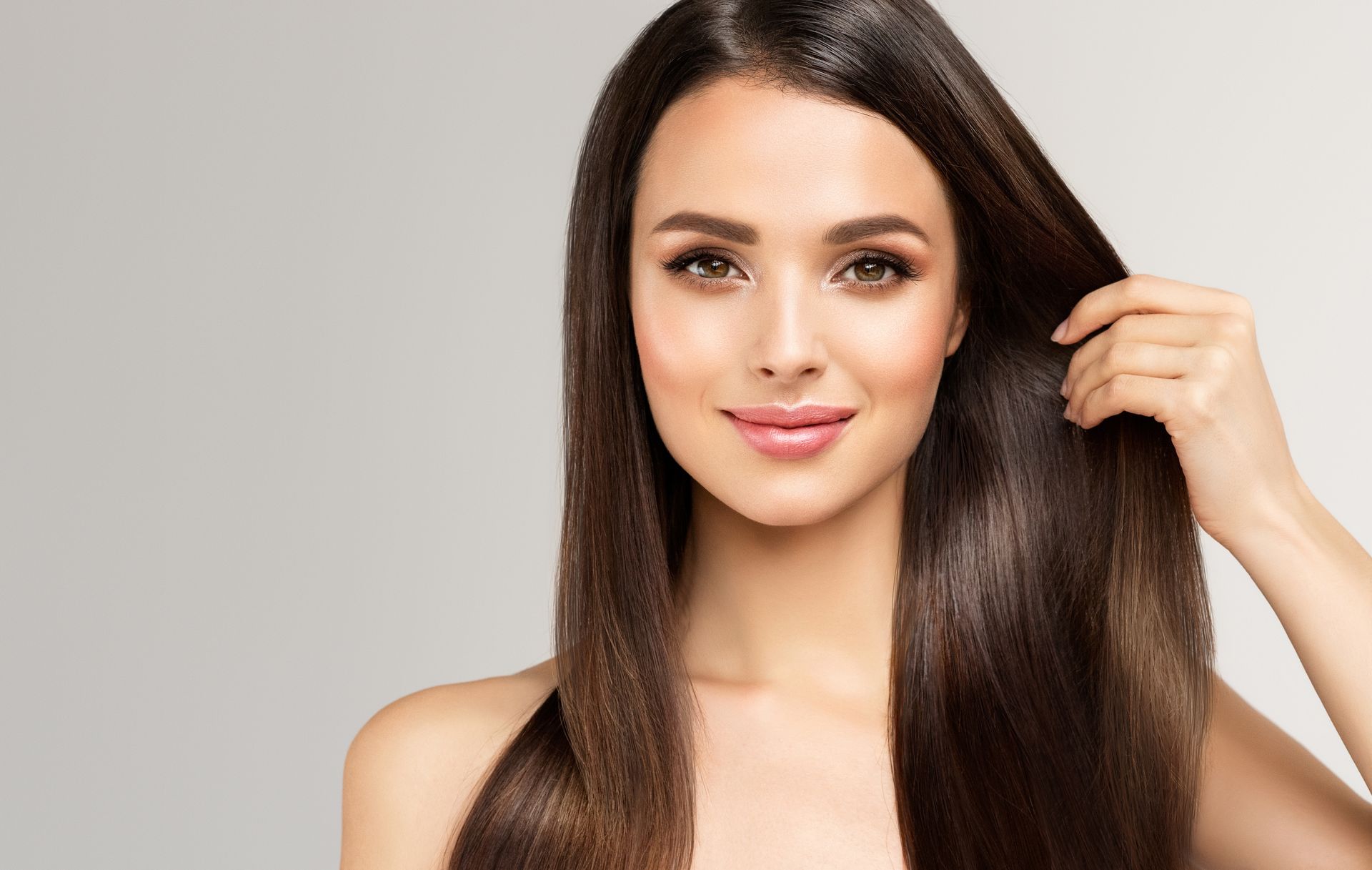 a woman with long hair is holding her hair in front of her face .