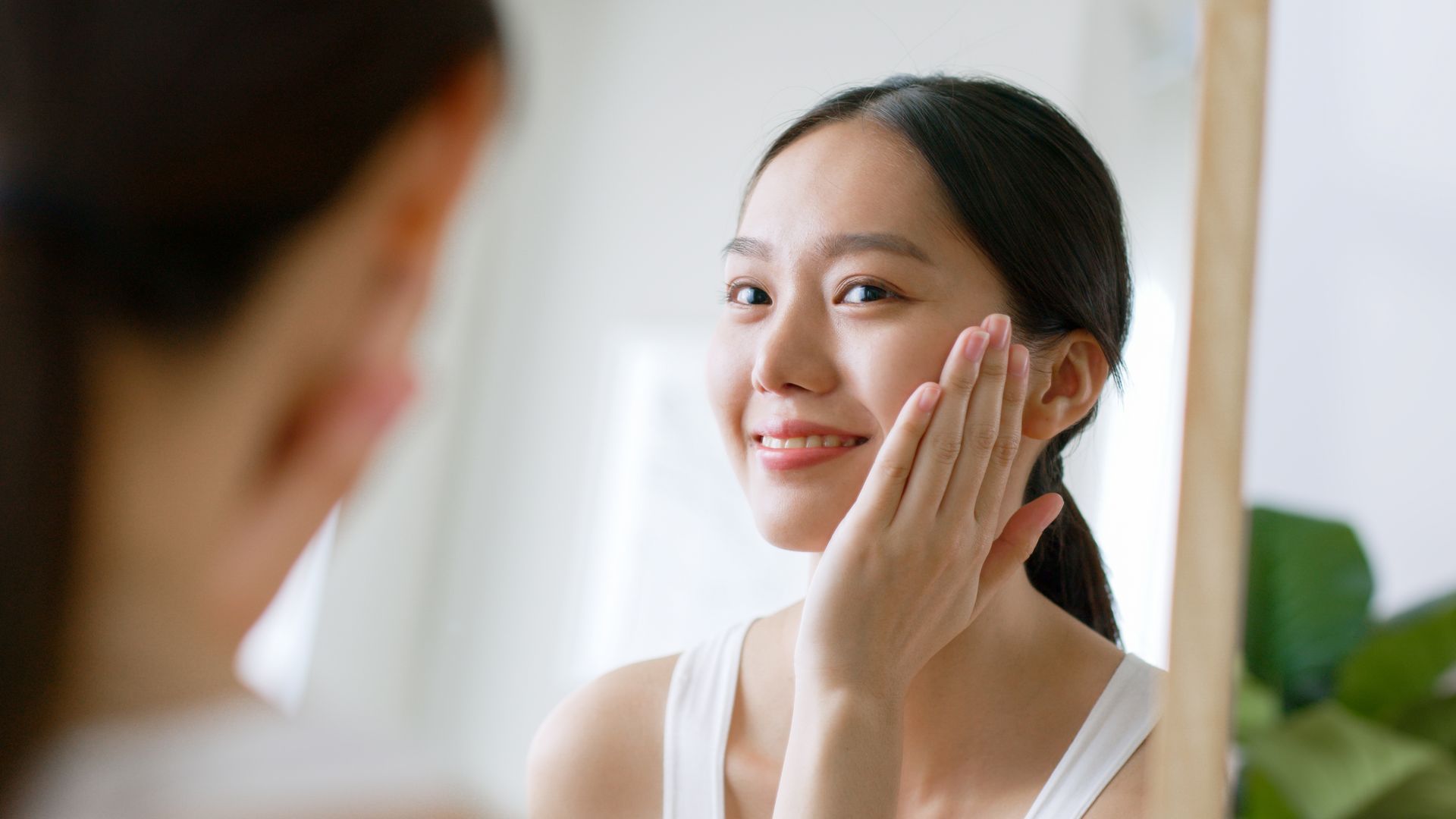 a woman is looking at her face in the mirror .