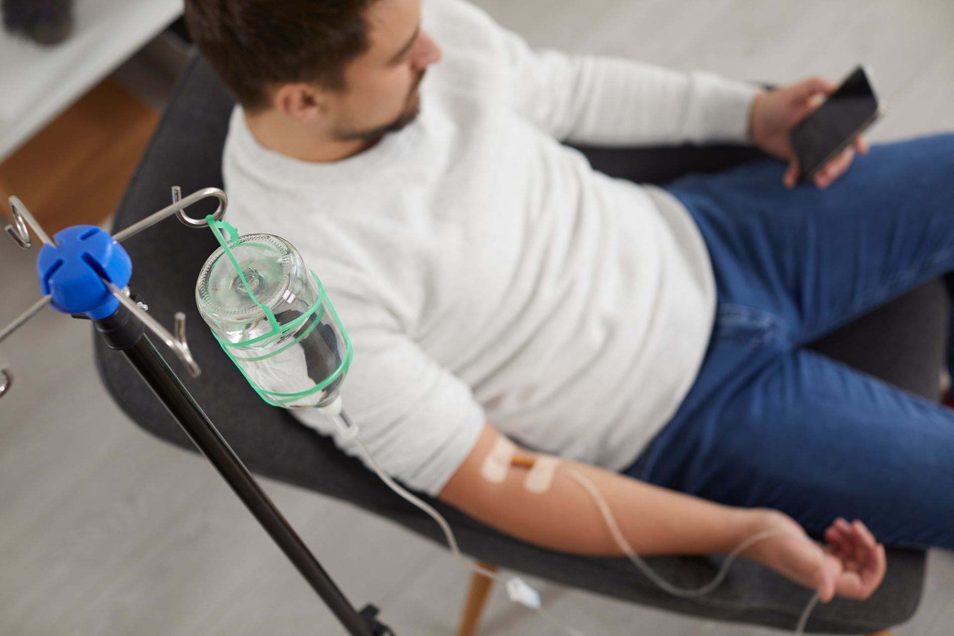 a man is sitting in a chair with an iv in his arm .