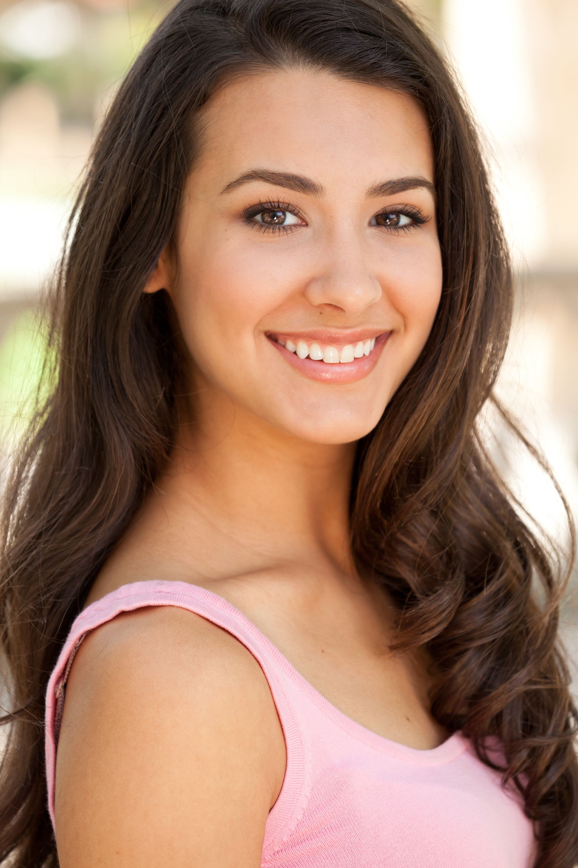 The woman is wearing a pink tank top and smiling for the camera.