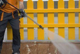 Jetclean operator using pressure cleaning equipment to efficiently power wash a fence and adjacent floors.