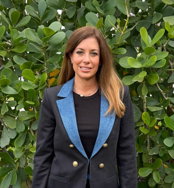 Woman in black turtleneck top, leaning on countertop, smiles.