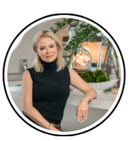 Woman in black turtleneck top, leaning on countertop, smiles.