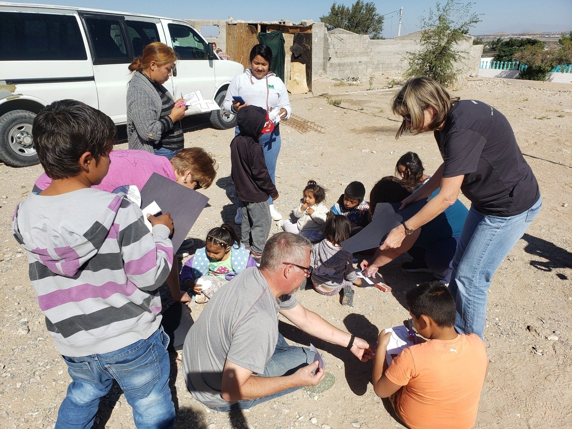 A group of people are gathered in a circle in the dirt
