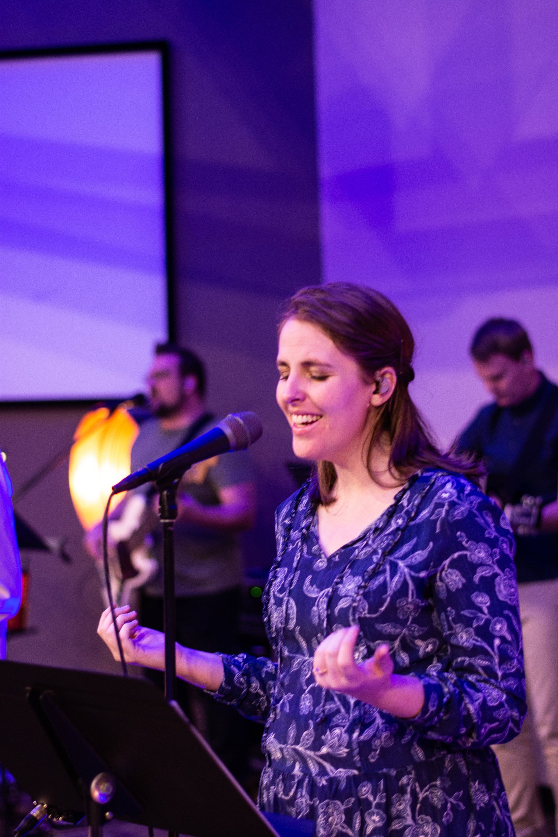 A woman is singing into a microphone on a stage.