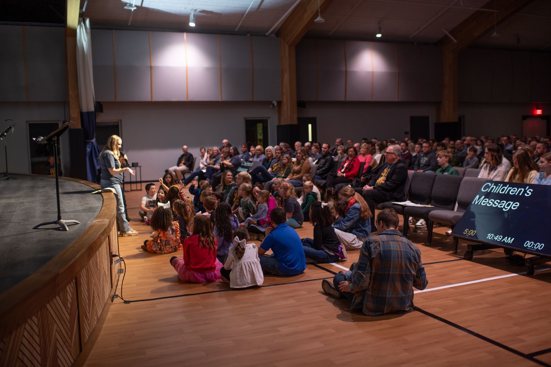 A group of people are sitting on the floor in front of a stage.