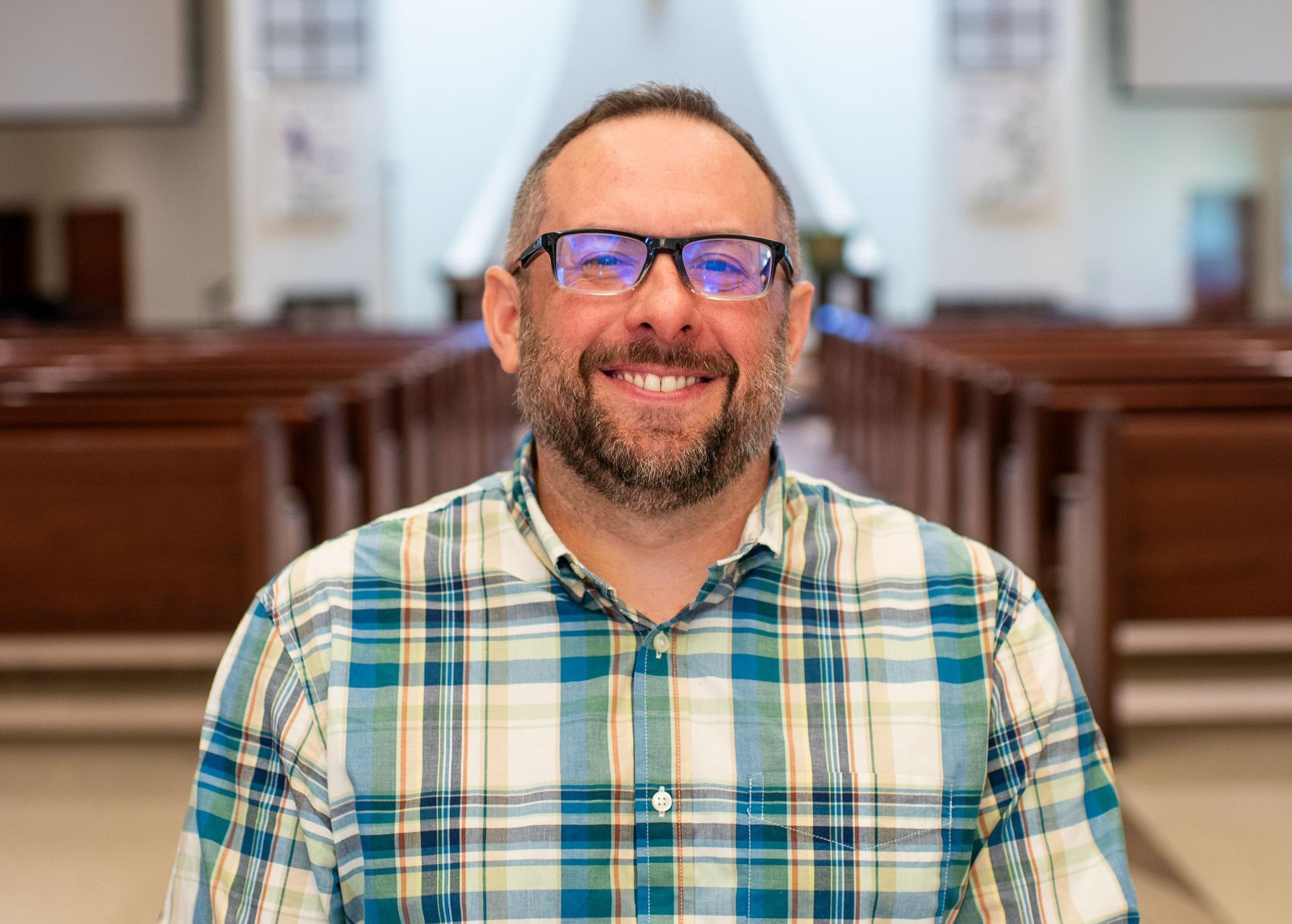 A woman in a white sweater is smiling in a church.
