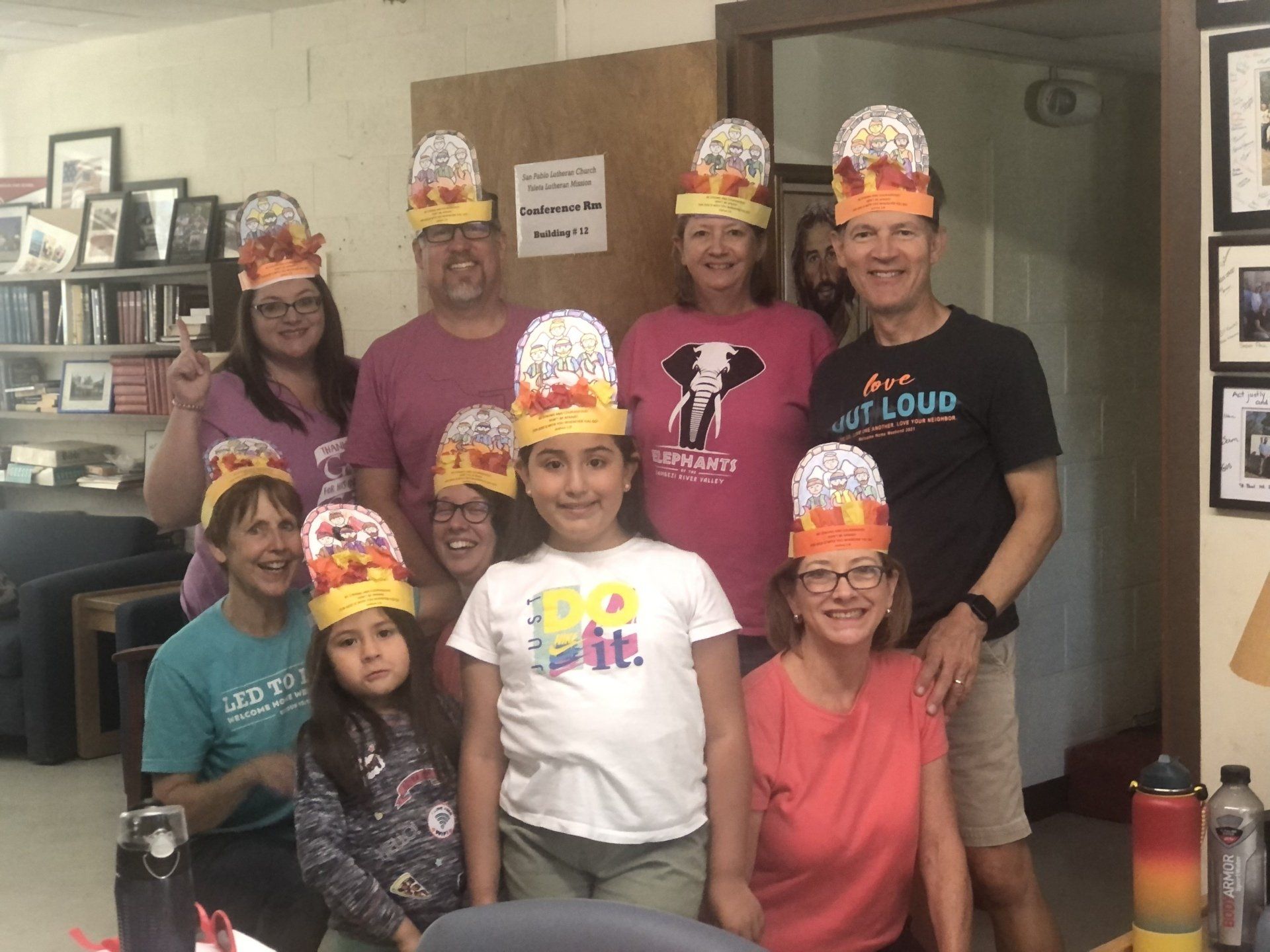 A group of people wearing paper crowns are posing for a picture.