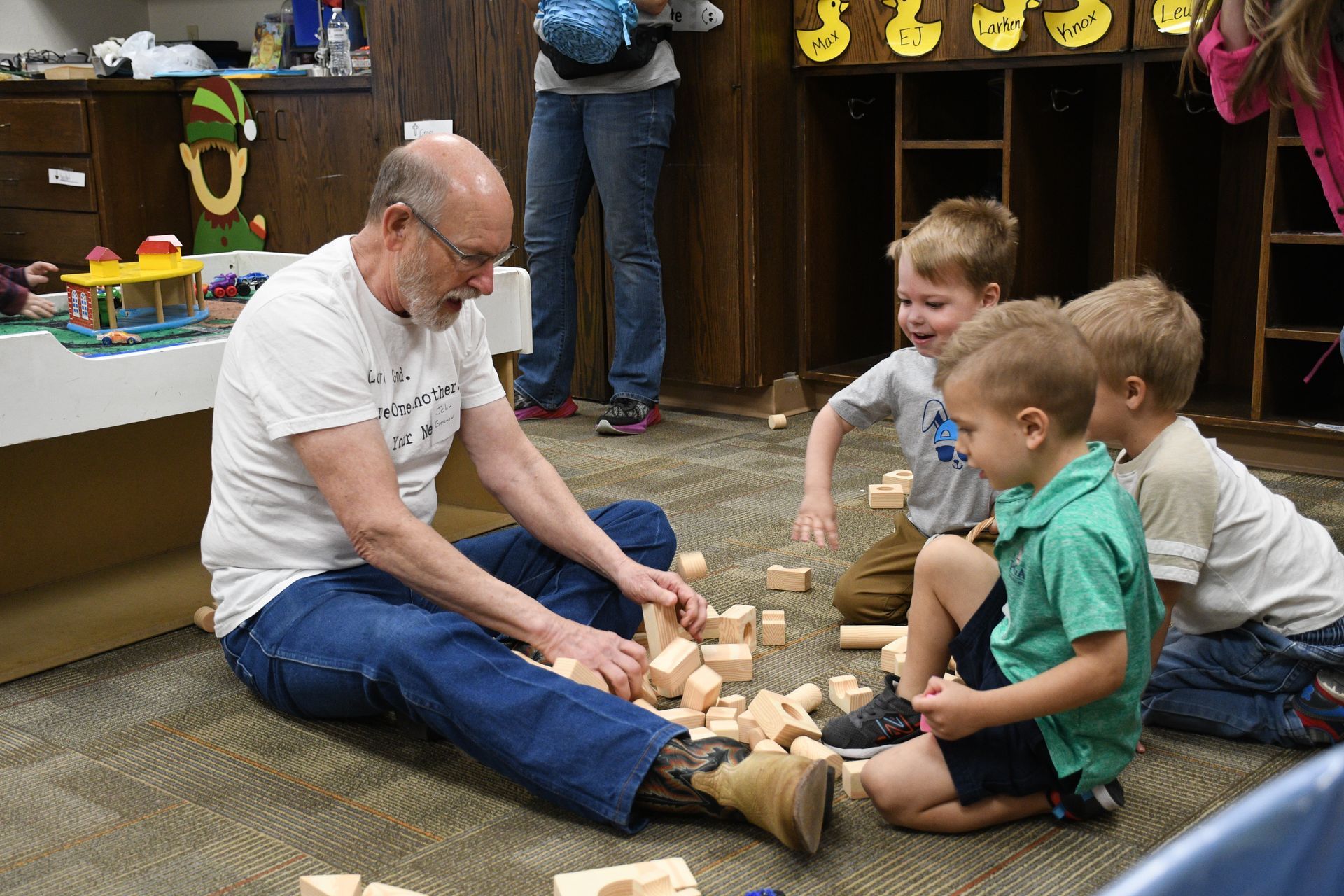 A man is sitting on the floor playing with children.