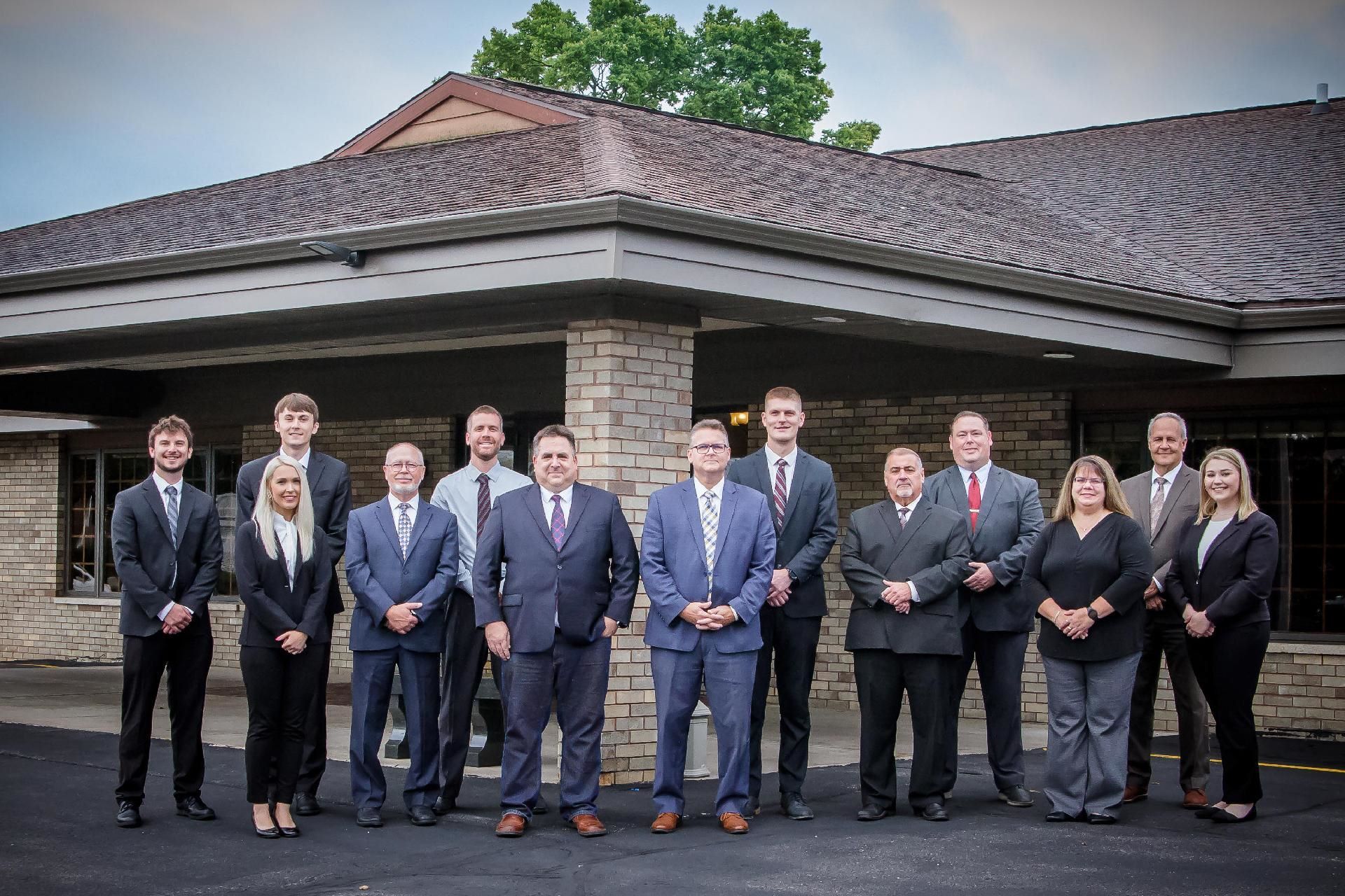 A group of people in suits and ties are posing for a picture in front of a building.