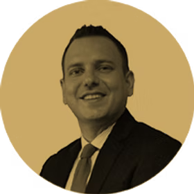 Man in suit smiling, with tie, in a sepia-toned circle.