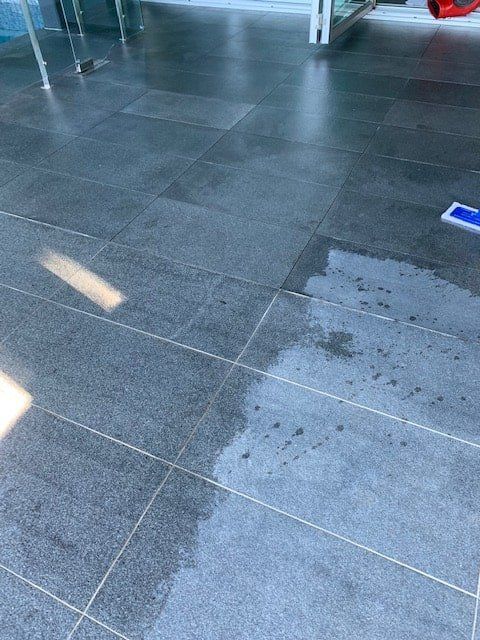 A Person is Cleaning a Tiled Floor With a Mop — The Tile & Stone Specialists in Peregian Beach, QLD