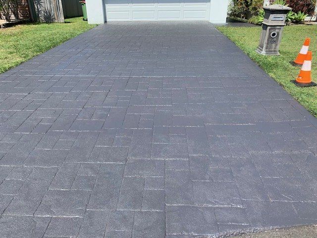 A Brick Driveway Leading to a Garage With Cones on the Side — The Tile & Stone Specialists in Peregian Beach, QLD