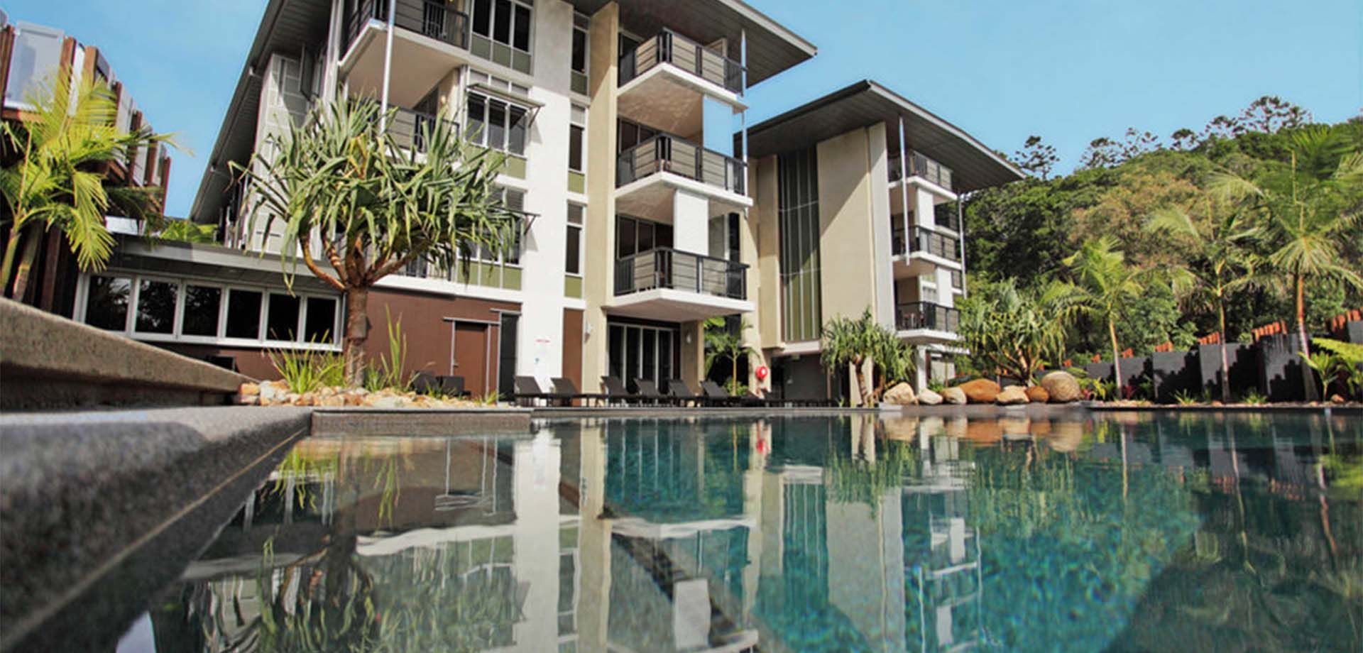 A Large Building With a Swimming Pool in Front of It — The Tile & Stone Specialists in Maroochydore, QLD