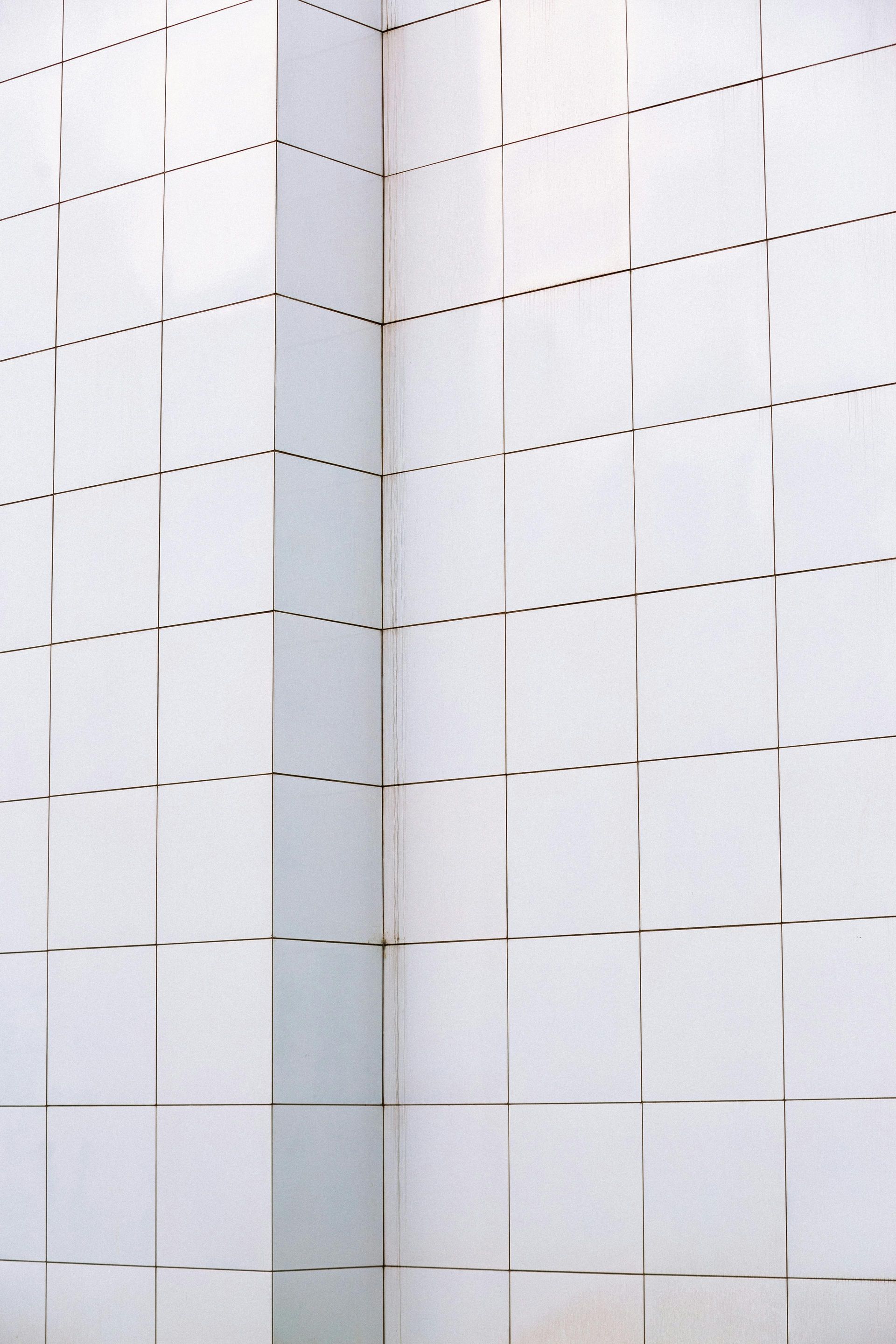 White tiled wall corner with dashed grid lines and vertical cracks