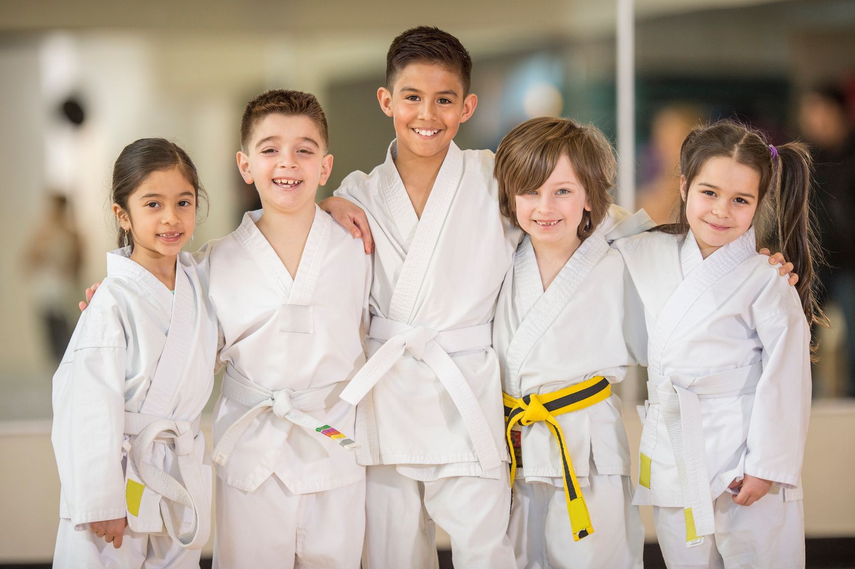 A group of young children in karate uniforms are posing for a picture.