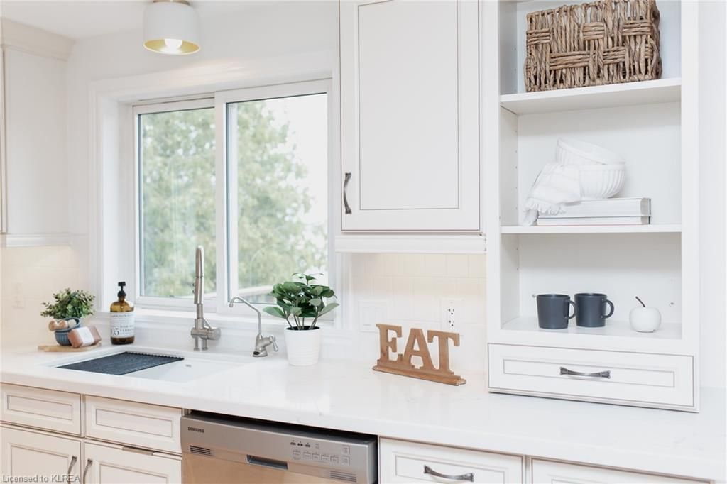 A kitchen with white cabinets , a dishwasher , a sink , and a sign that says eat.