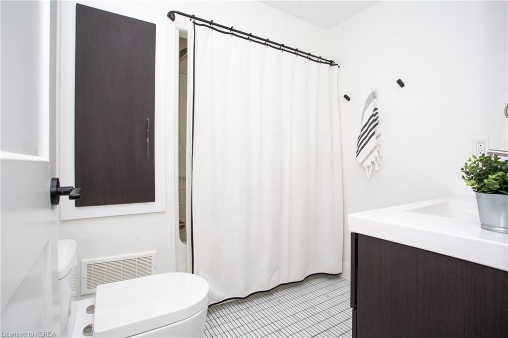 A bathroom with a toilet , sink and shower curtain.