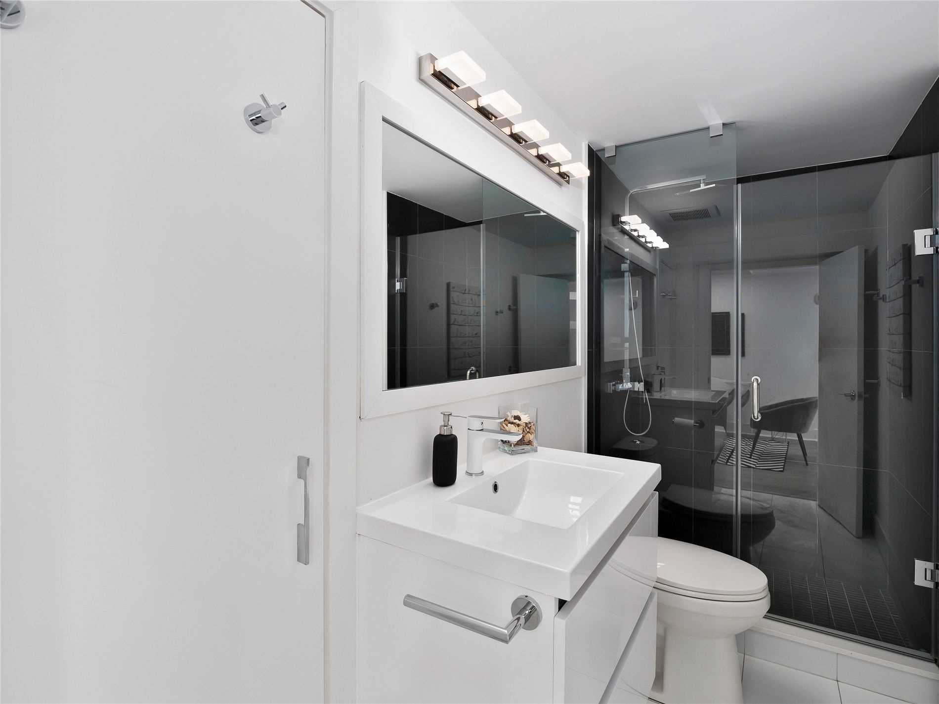 A bathroom with a sink , toilet , mirror and shower.