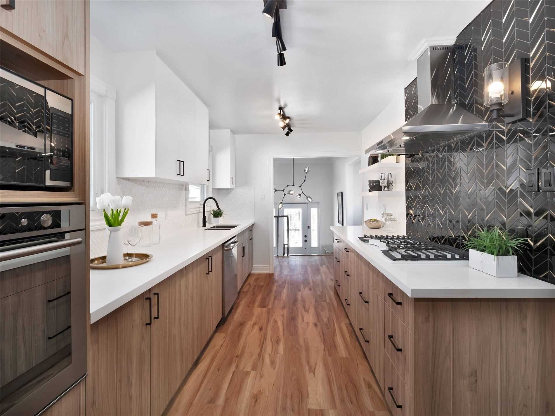 A kitchen with wooden cabinets , white counter tops , and stainless steel appliances.