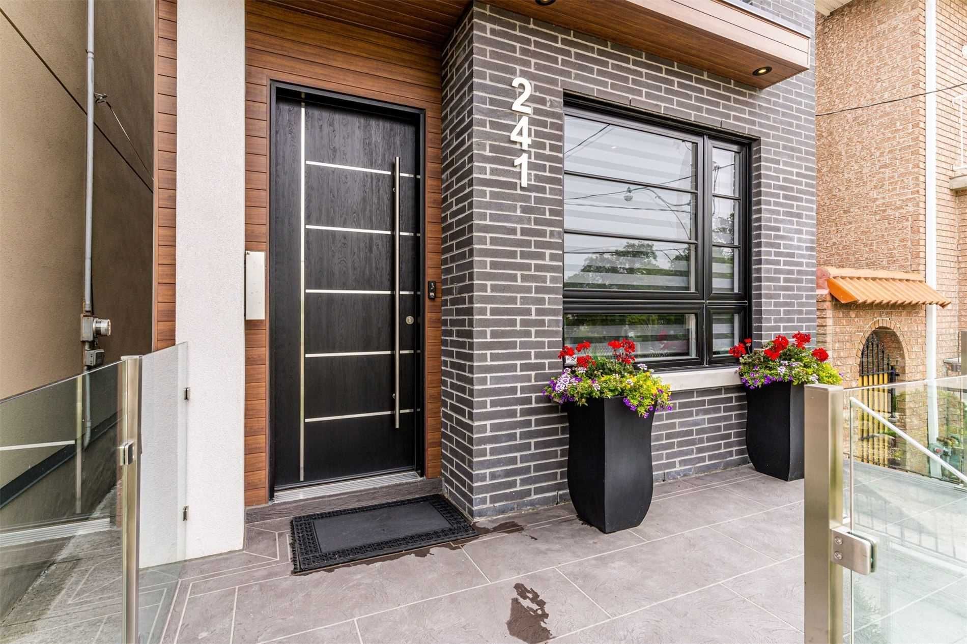 The front of a brick house with a black door and a large window.