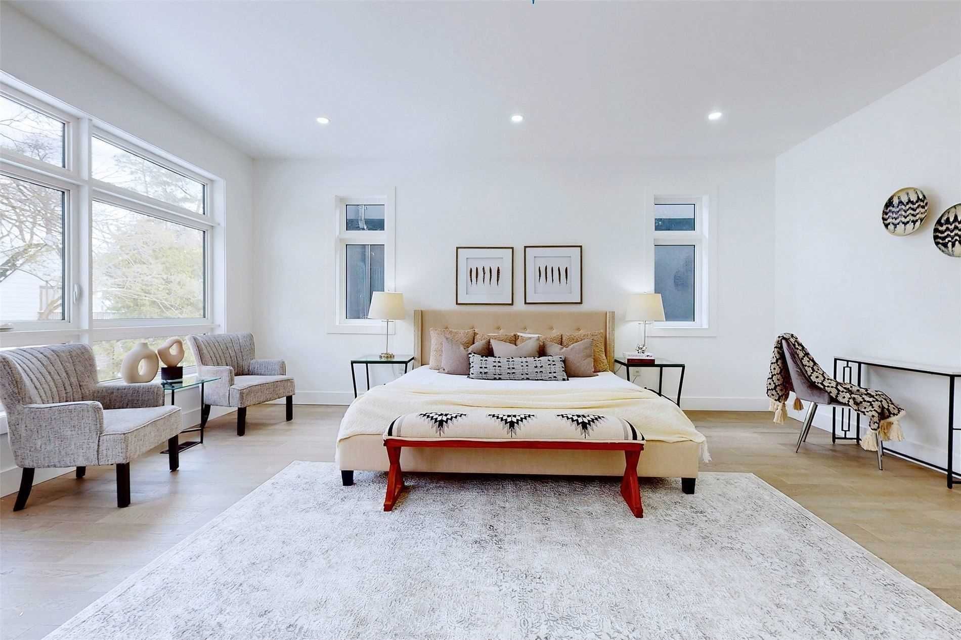 A bedroom with a large bed , chairs , lamps and a rug.