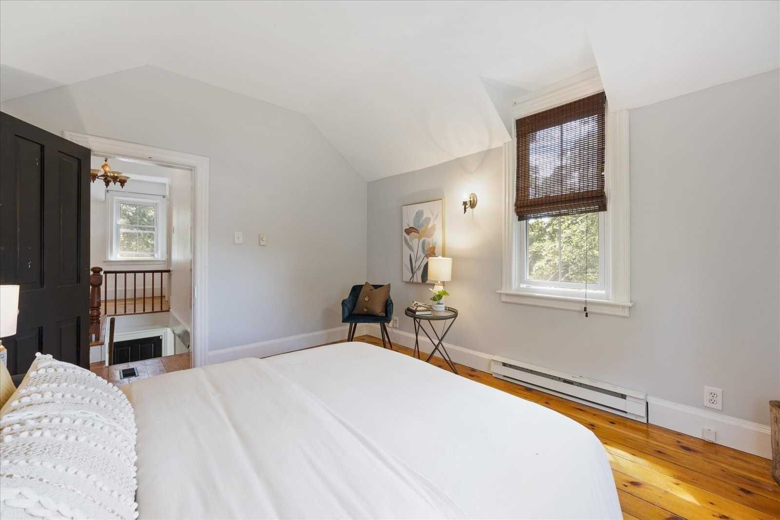 A bedroom with a large bed , chair , table and window.