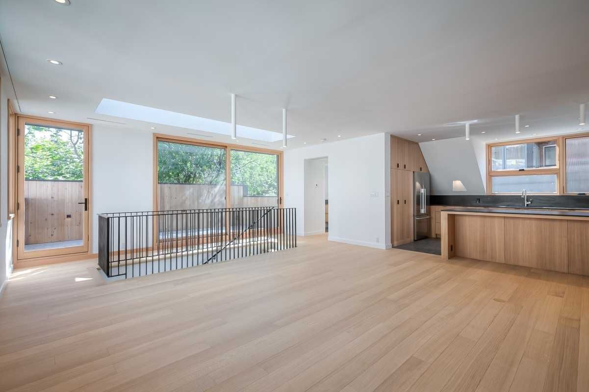 A large empty room with hardwood floors and a kitchen.