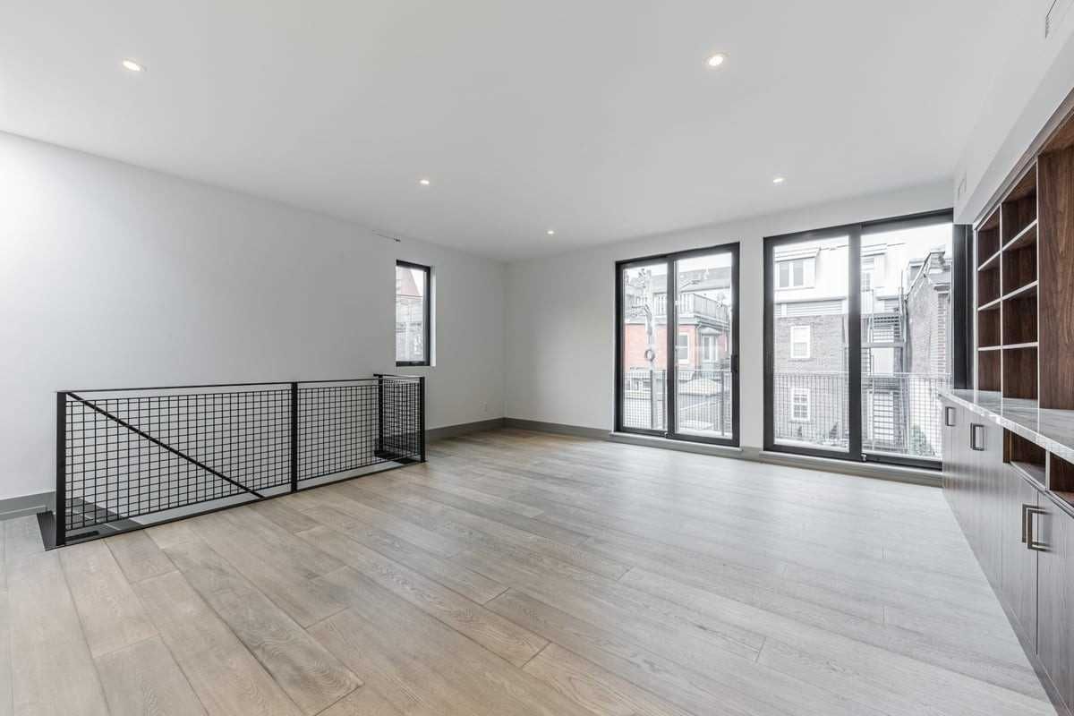 An empty living room with hardwood floors and lots of windows.