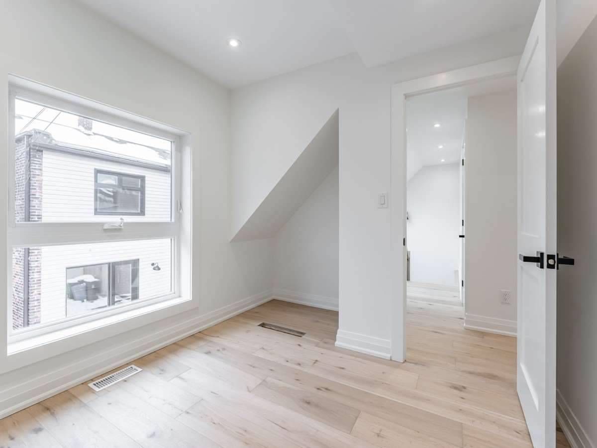 An empty room with hardwood floors and two windows.