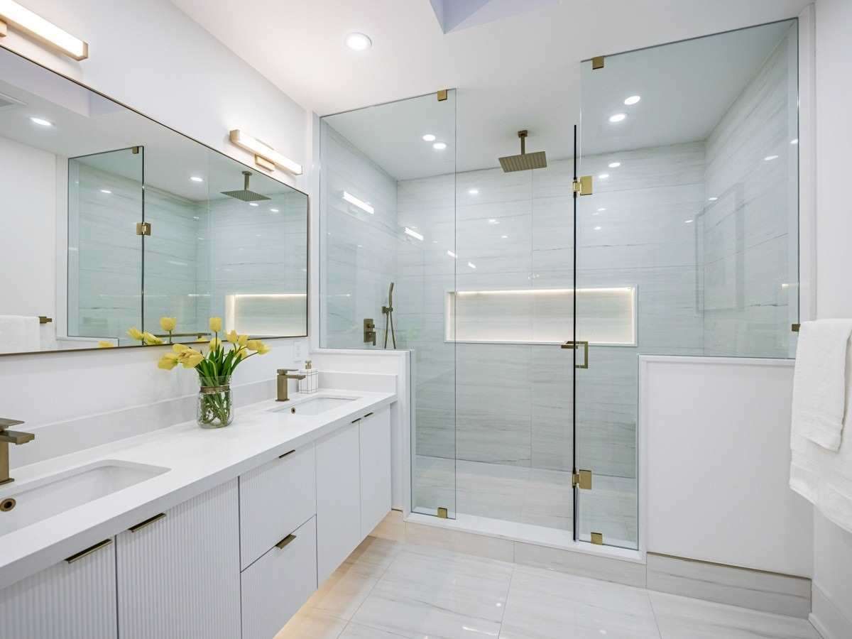 A bathroom with two sinks and a walk in shower.