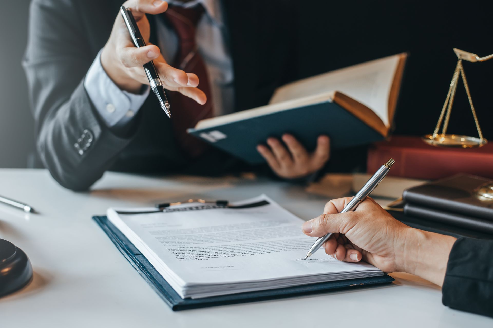 Lawyers reviewing documents at a desk with a gavel and scales of justice in the background