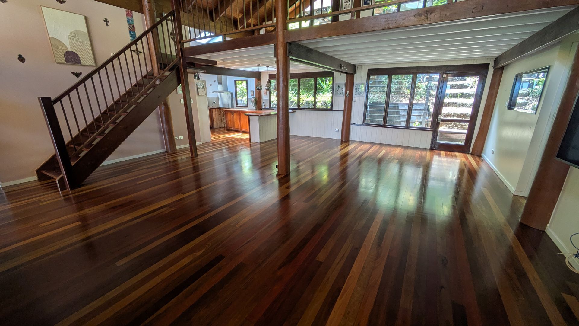 Interior view of a house with wooden floors, staircase, and windows.