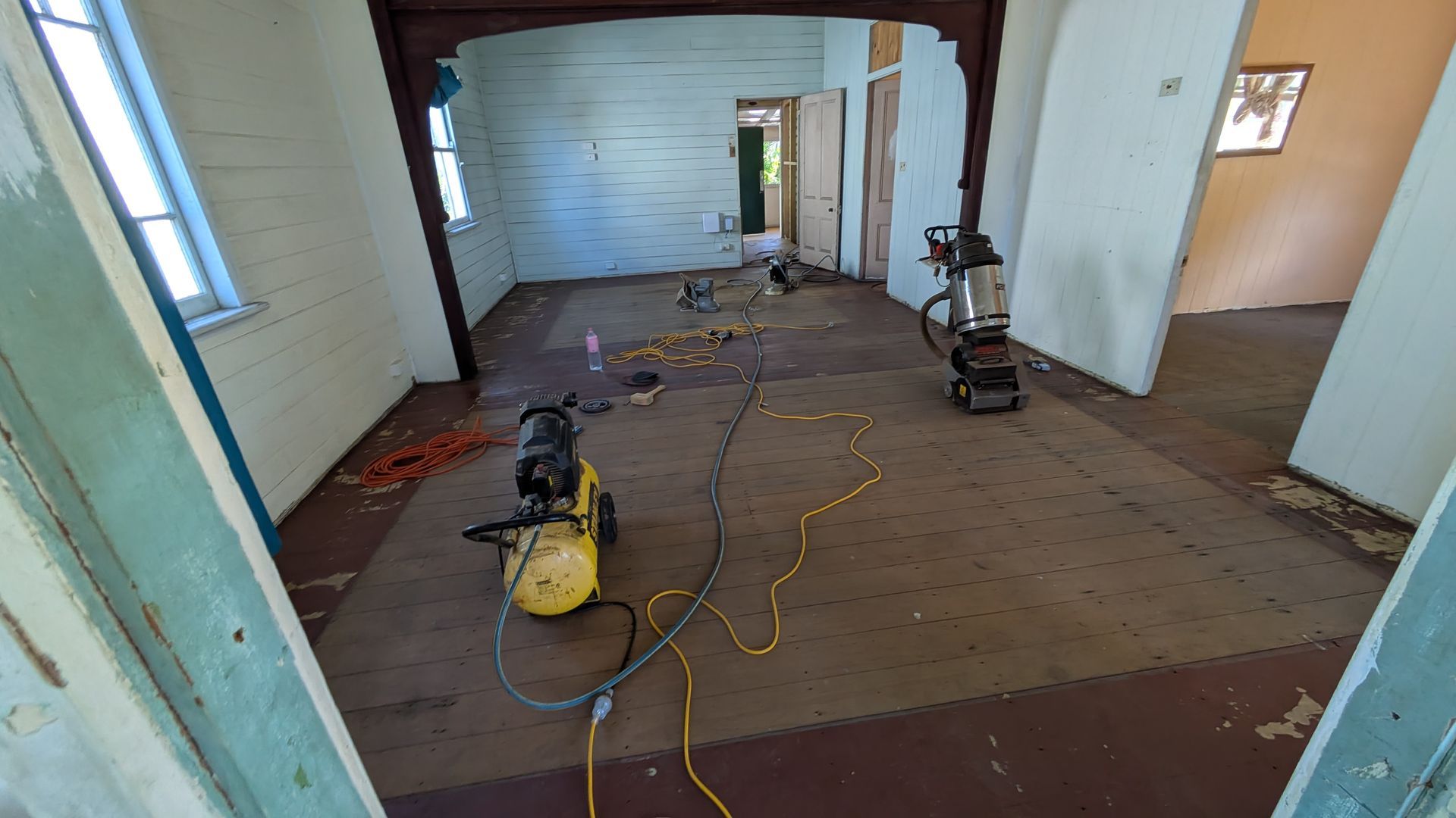 Interior room undergoing renovation; tools on floor, open doorway, wooden walls.