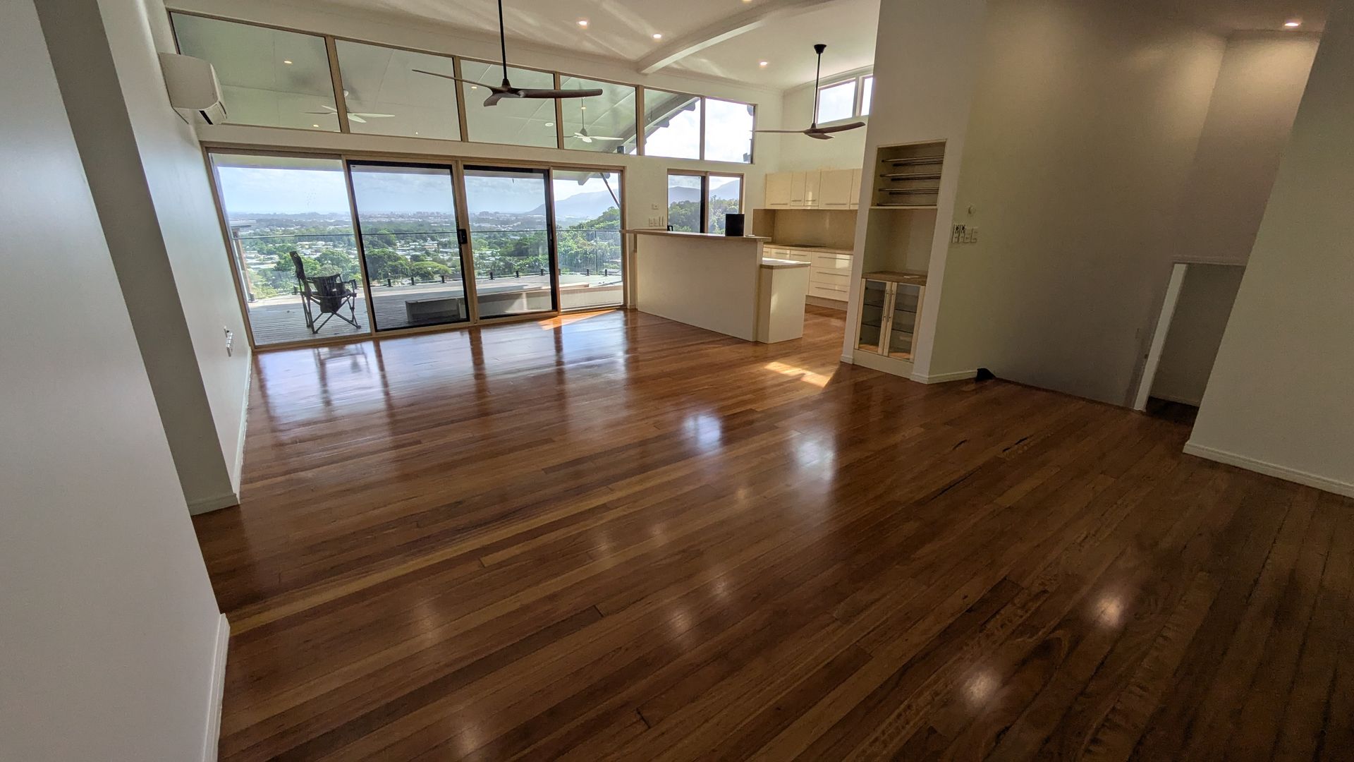 Spacious living area with wooden floors, large windows, and a view of the outdoors.