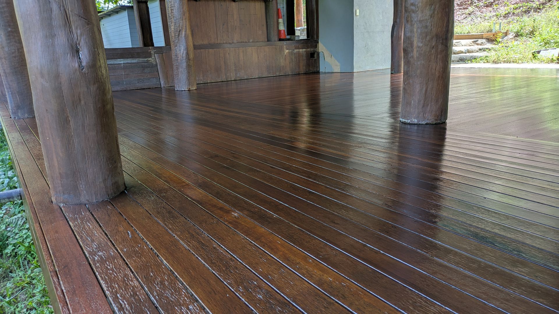 Dark wood deck with shiny finish, surrounded by wooden posts.