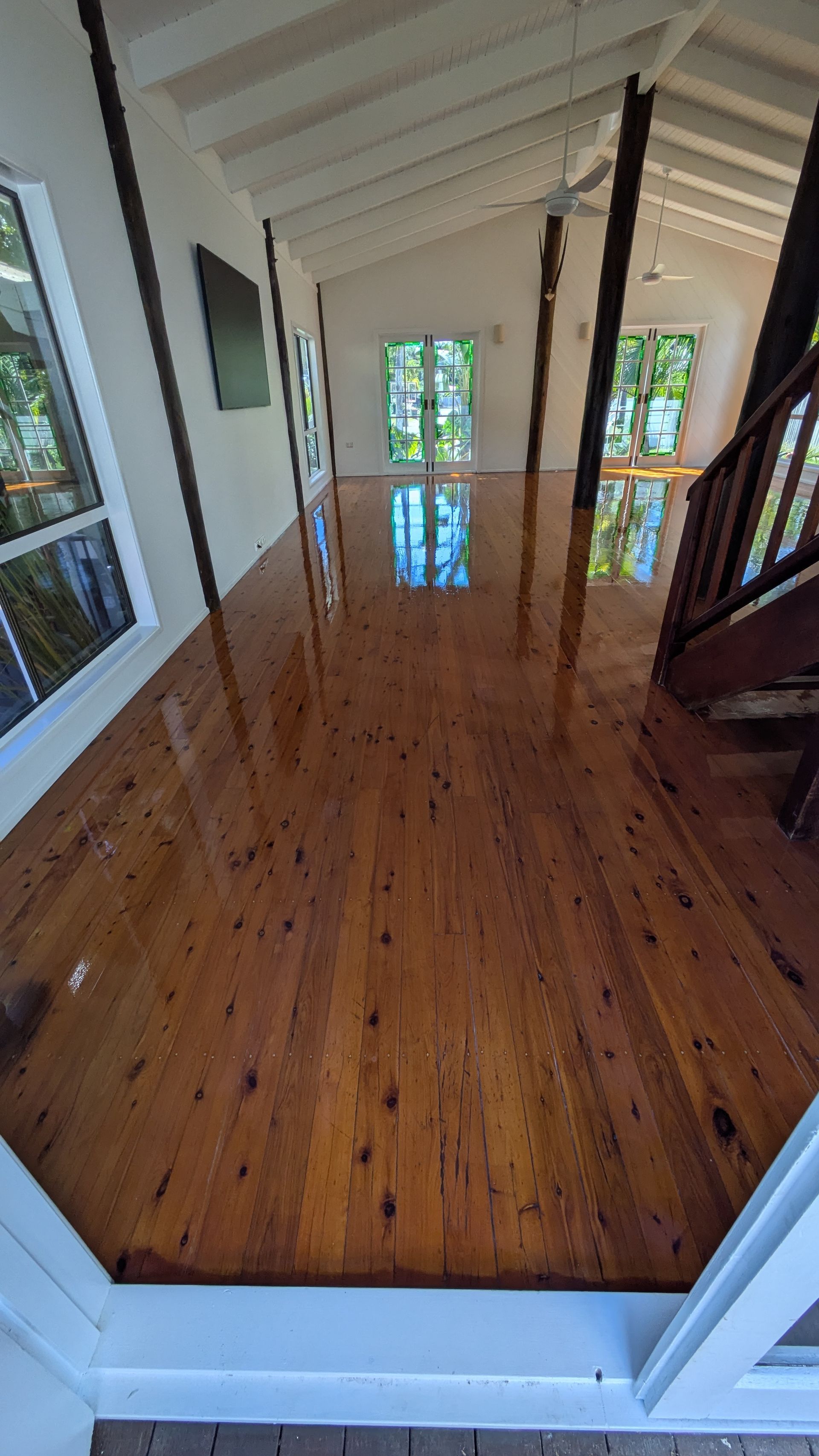 Shiny, wooden floor in a bright room with white walls and a staircase on the right.