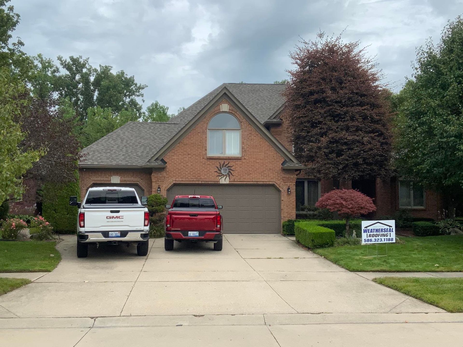 Two trucks are parked in front of a brick house
