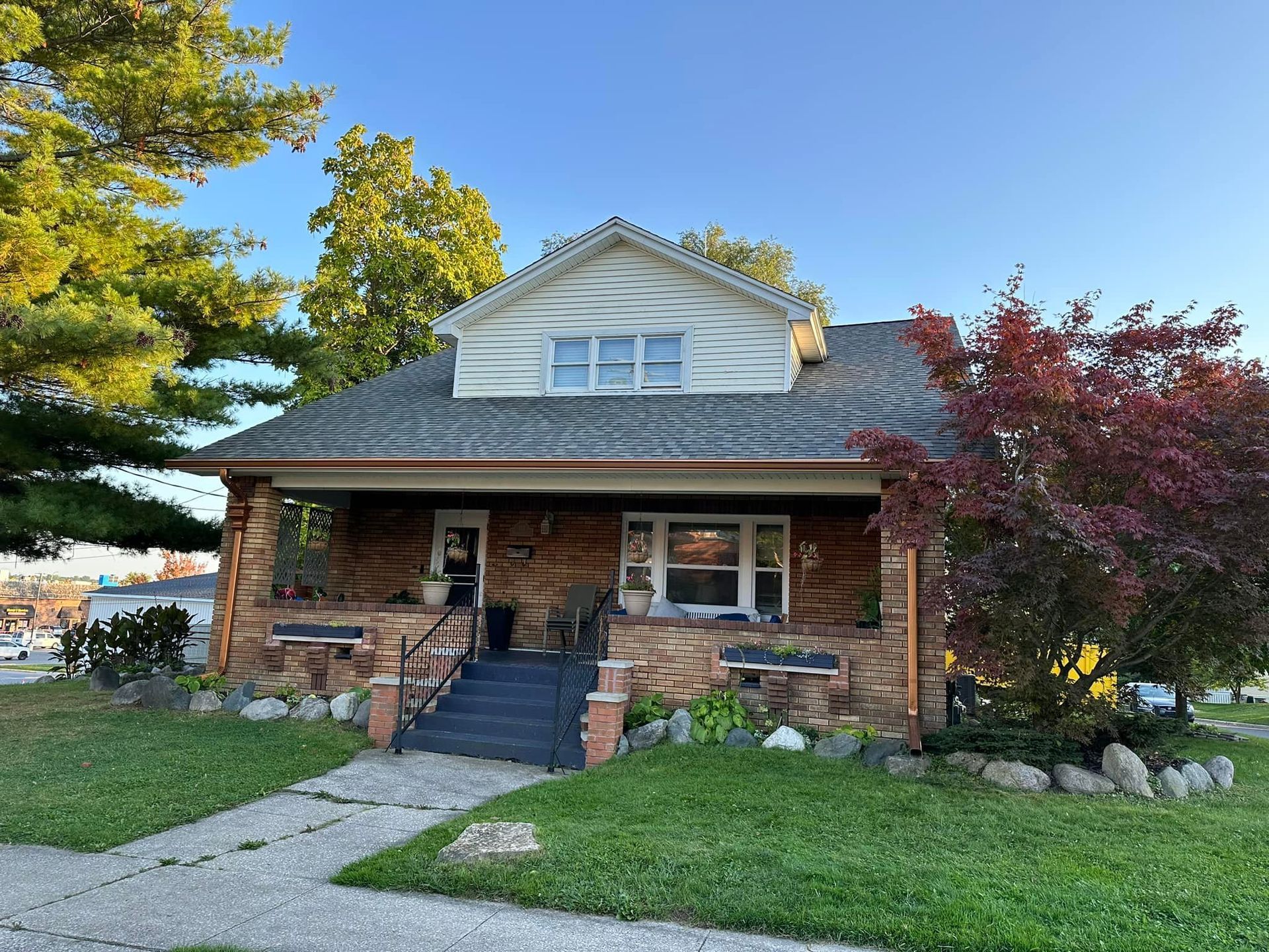 A brick house with a porch and stairs is for sale.