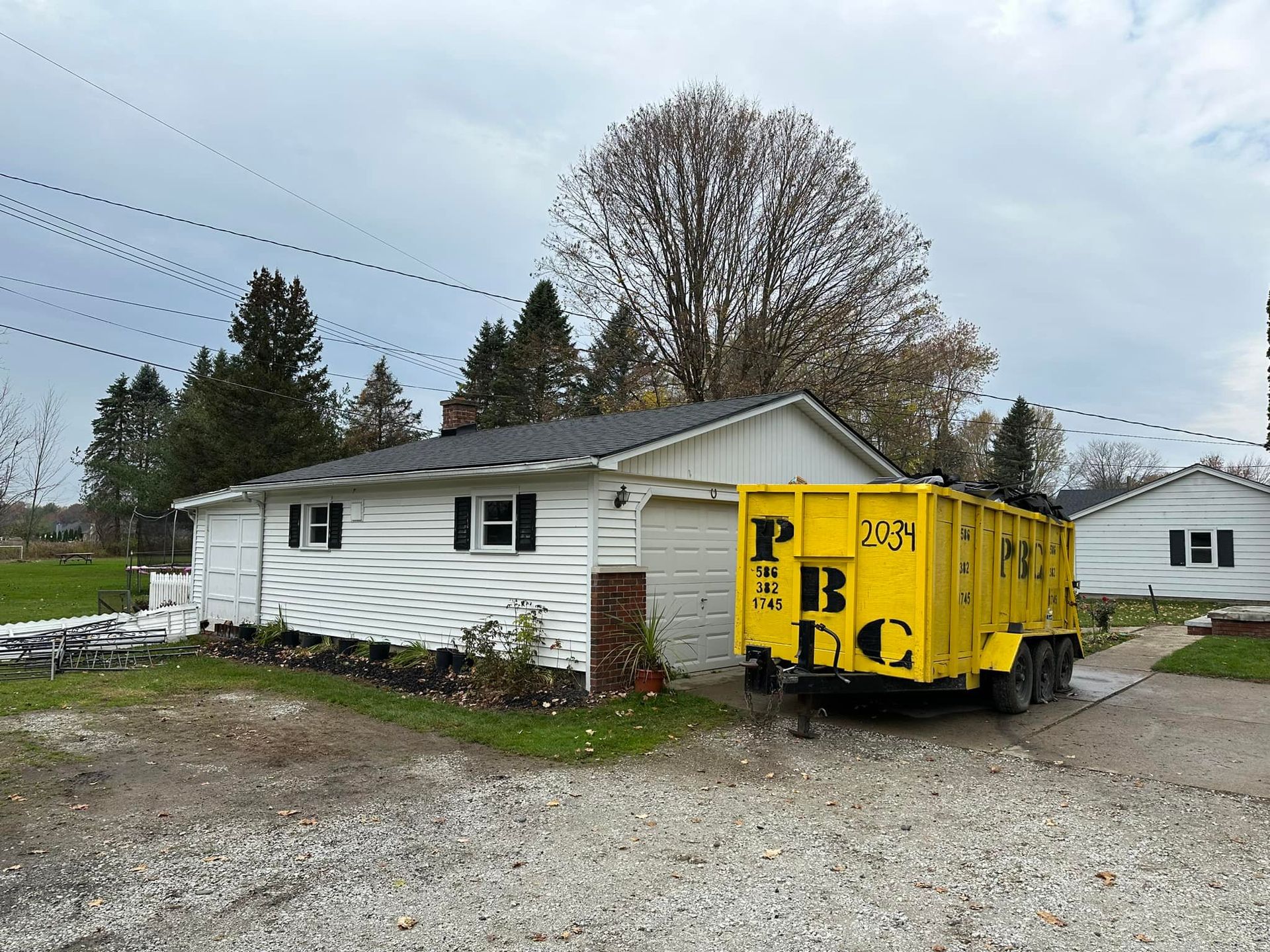 A yellow dumpster is parked in front of a house.