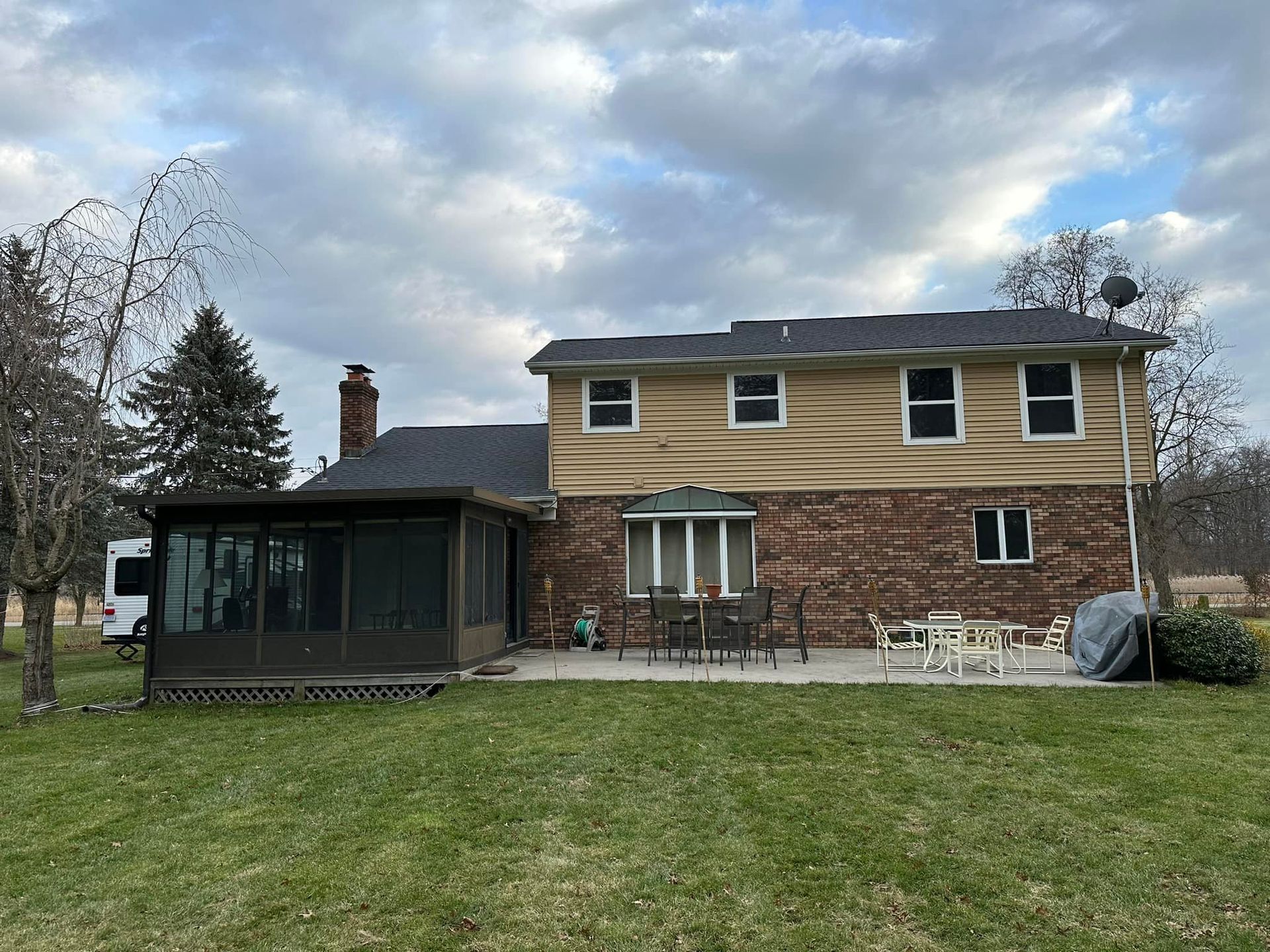 A large brick house with a screened in porch and patio.