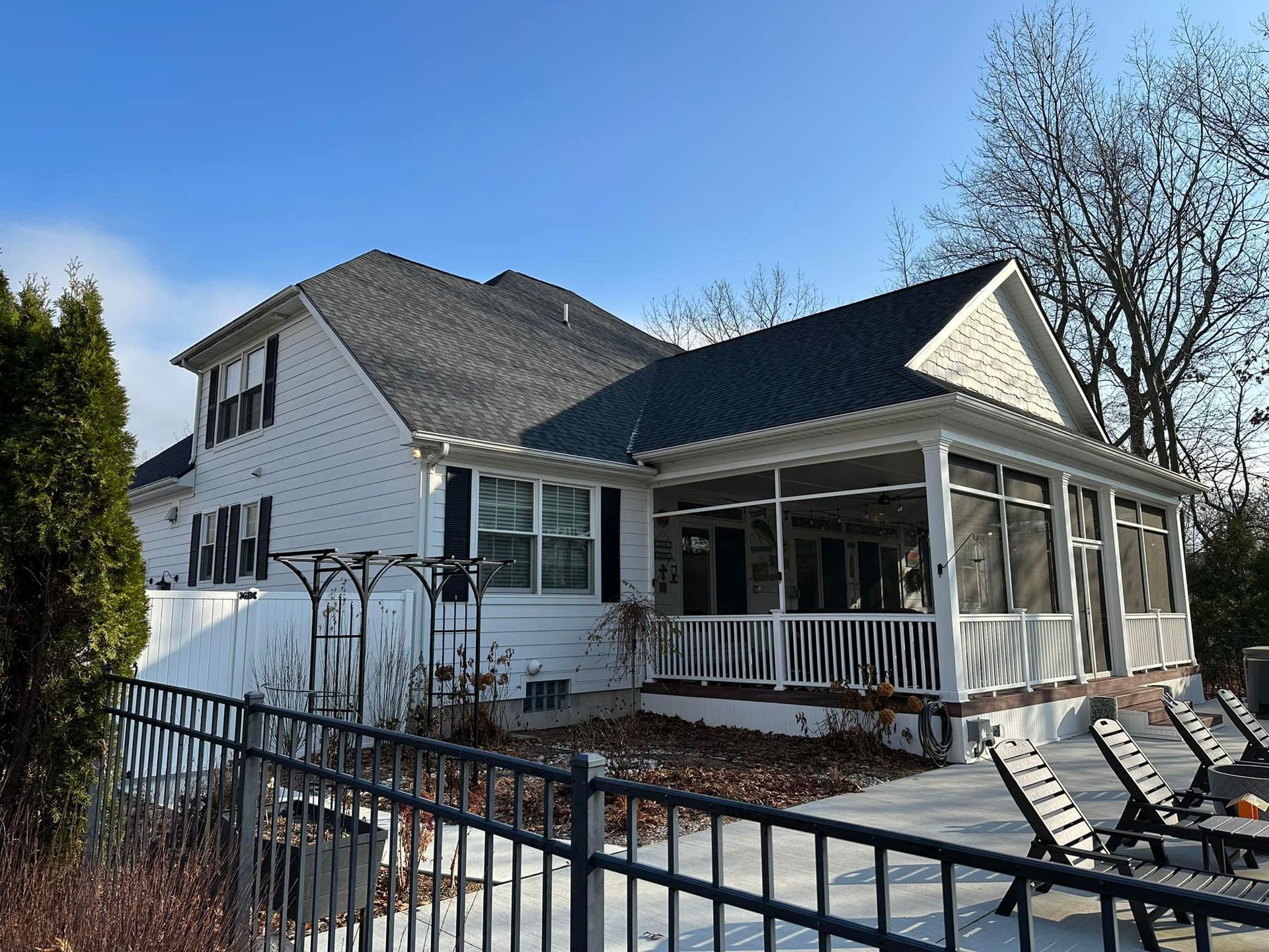 A white house with a screened in porch and a black fence