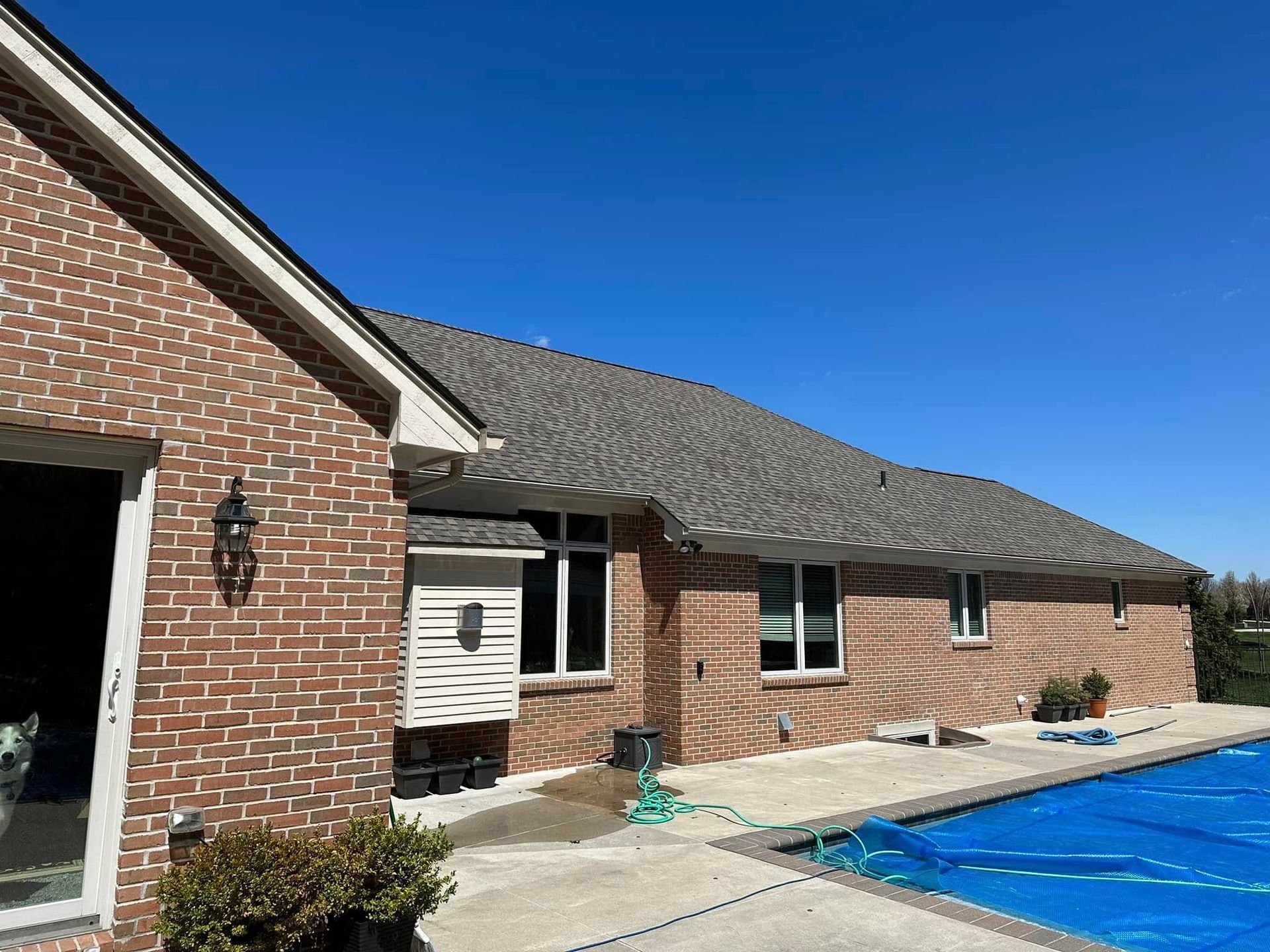 A brick house with a swimming pool in front of it.