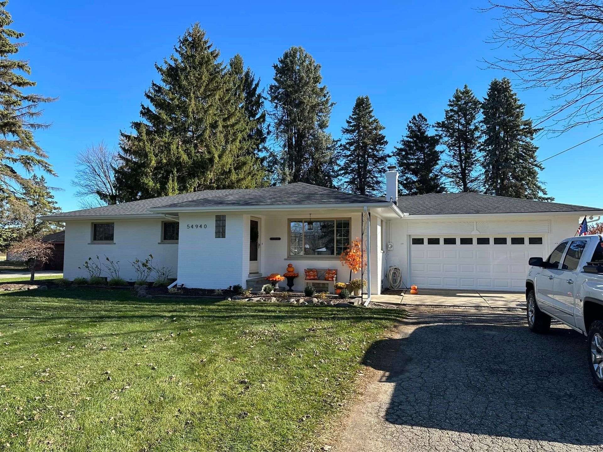 A white truck is parked in front of a white house
