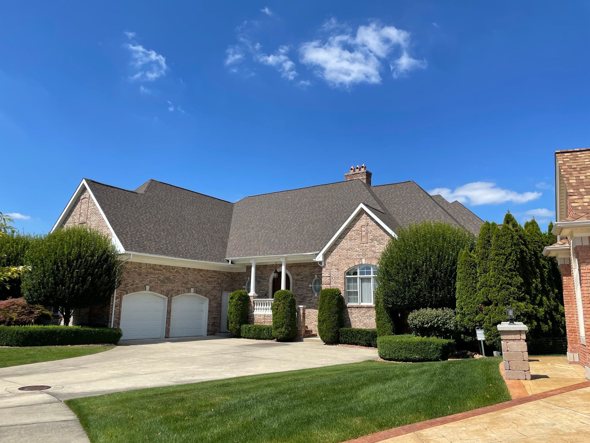 A large brick house with a gray roof and two garages.
