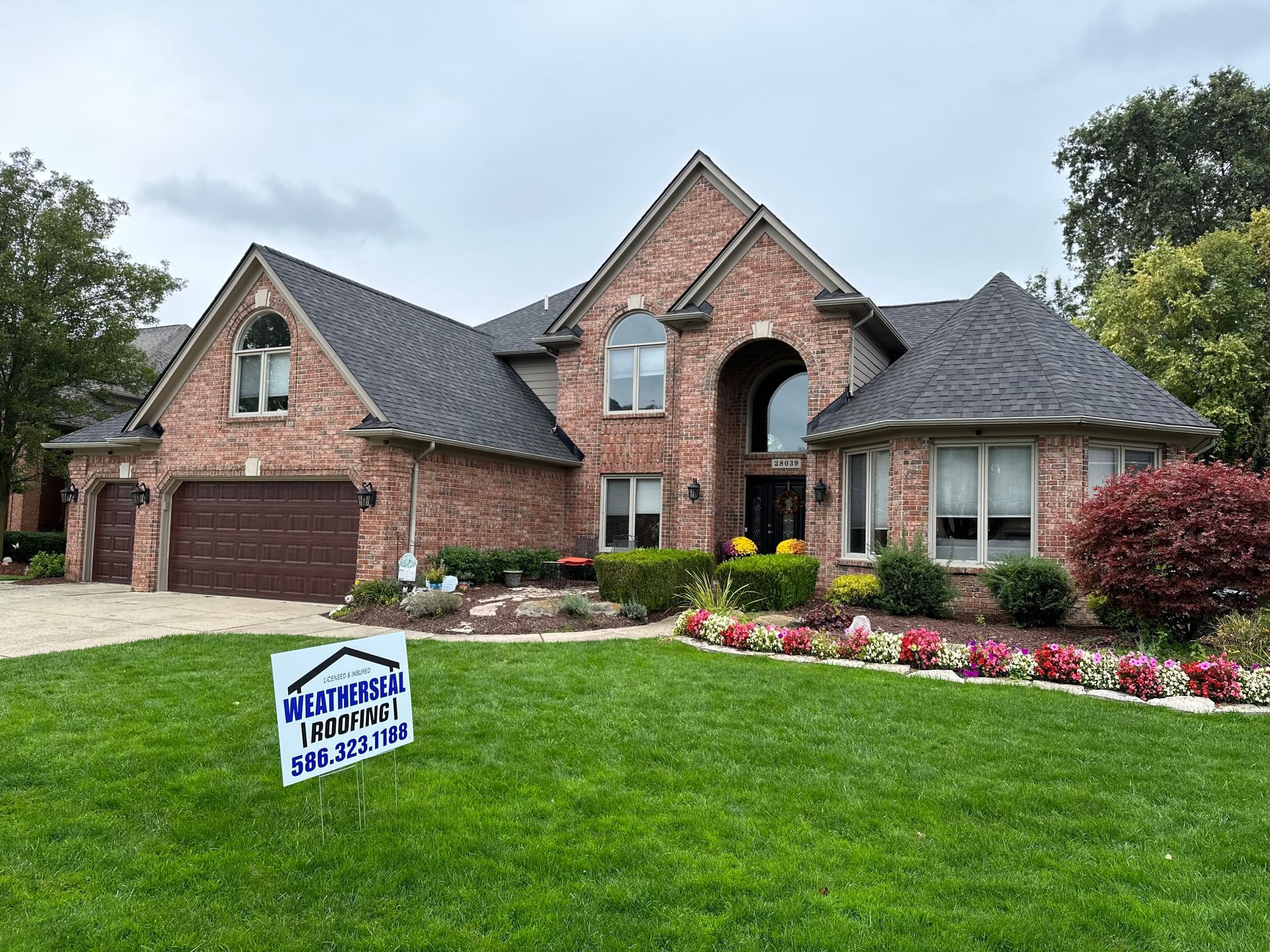 A large brick house with a sign in front of it.