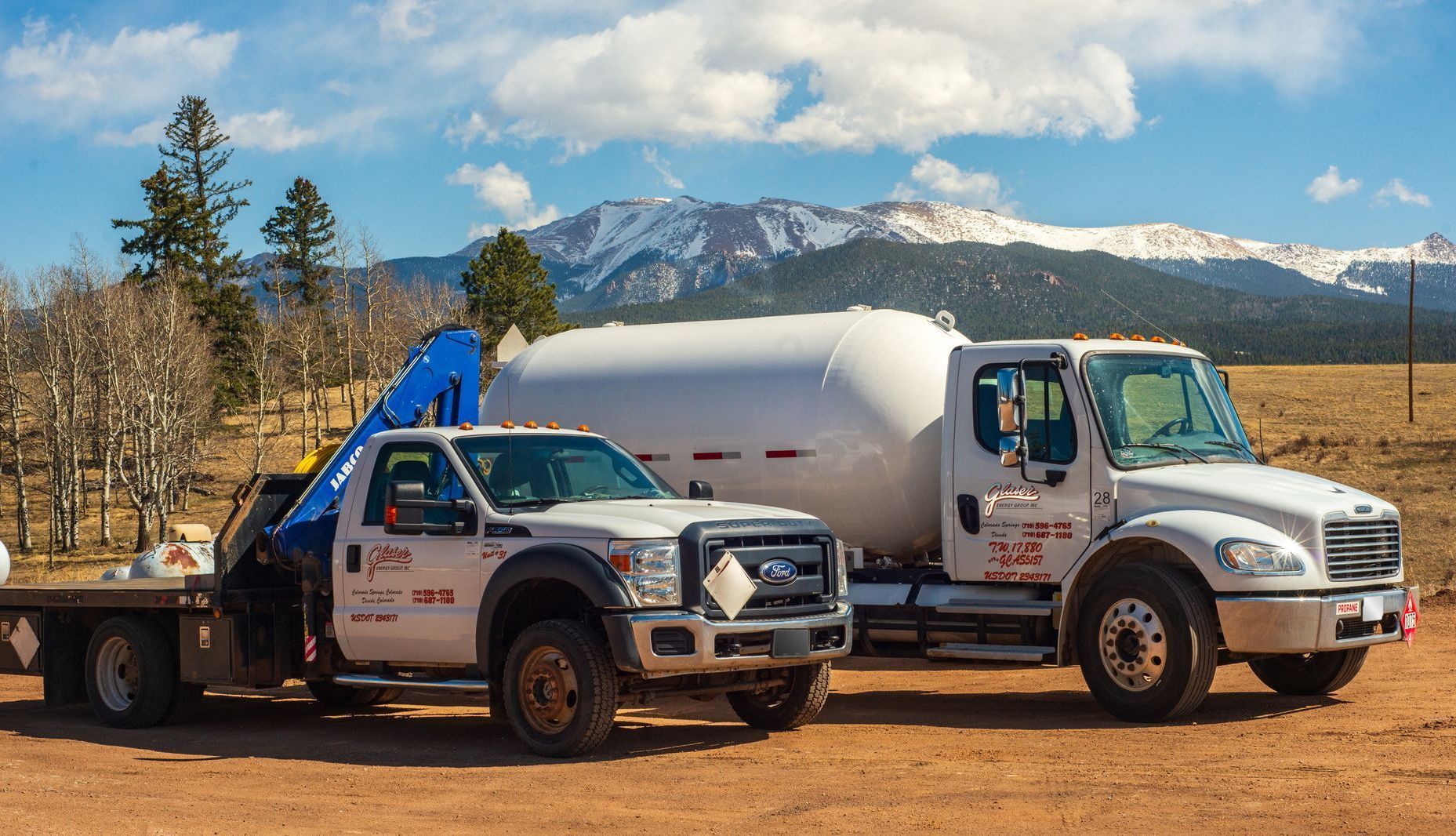 A man is standing next to a tanker truck in a parking lot