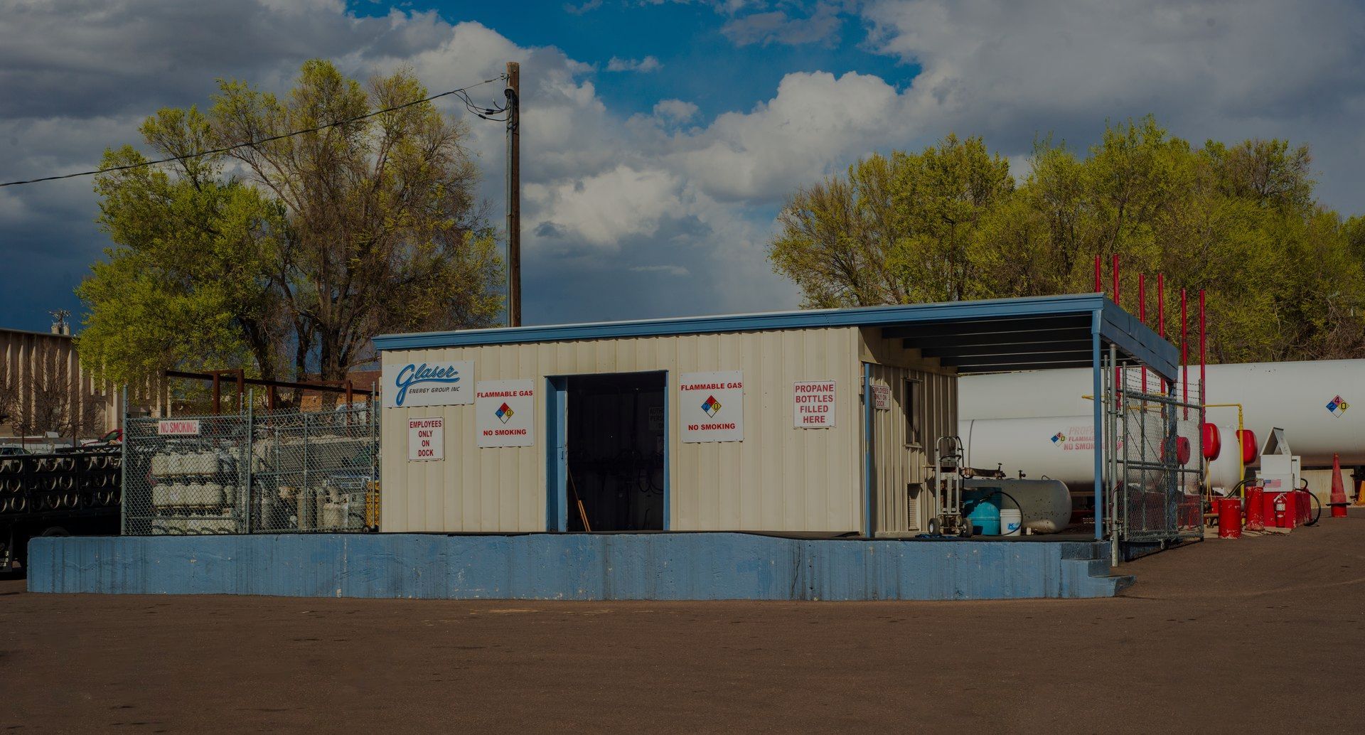 A white propane truck is parked in a dirt field.