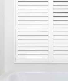 White Bathroom Window With Slatted Shutters Above a White Bathtub — GV Blinds in Shepparton, VIC