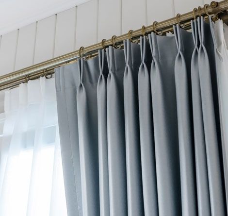 Close-up of Gray, Pleated Curtains Hanging From a Gold Rod — GV Blinds in Shepparton, VIC